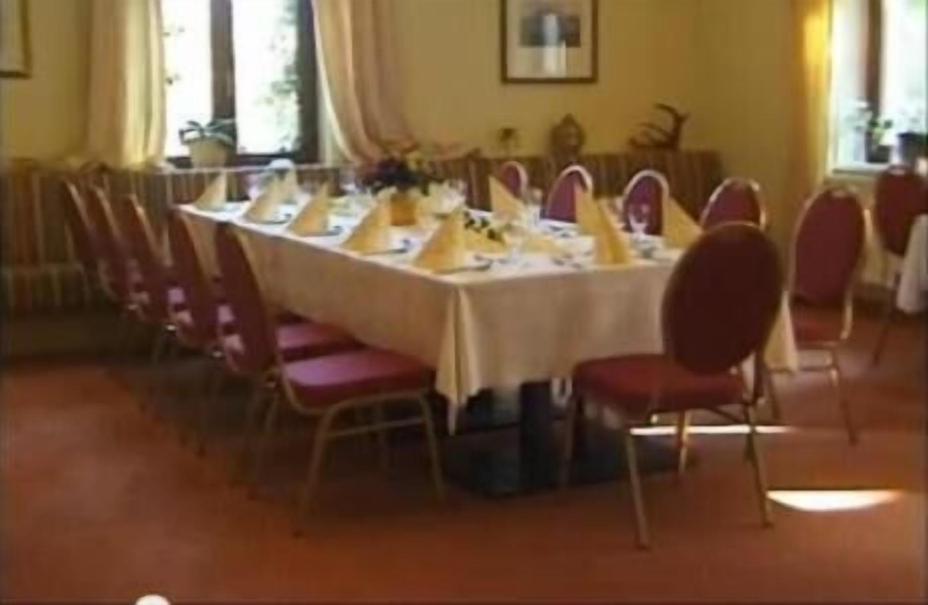 A dining area with a long table set for a meal, surrounded by red chairs.