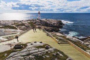 A coastal walkway leading to a lighthouse, surrounded by rocky terrain and the ocean.