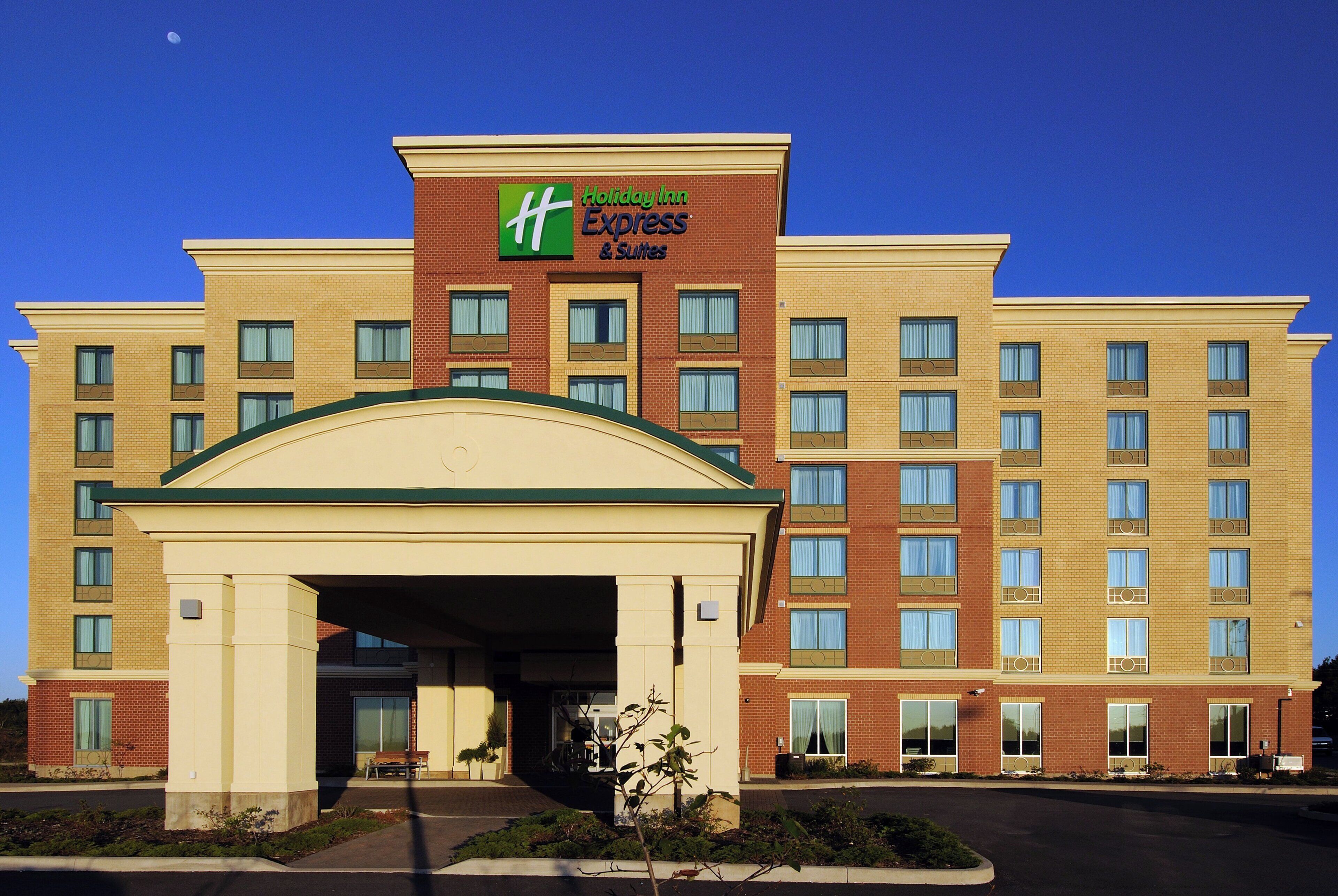 Un hôtel Holiday Inn Express & Suites avec une façade en briques, de nombreuses fenêtres et une entrée centrale.