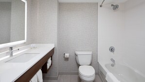 A modern bathroom with a white sink, toilet, and bathtub, featuring a large mirror and a towel rack. - Holiday Inn Express & Suites Halifax Airport by IHG (Goffs)