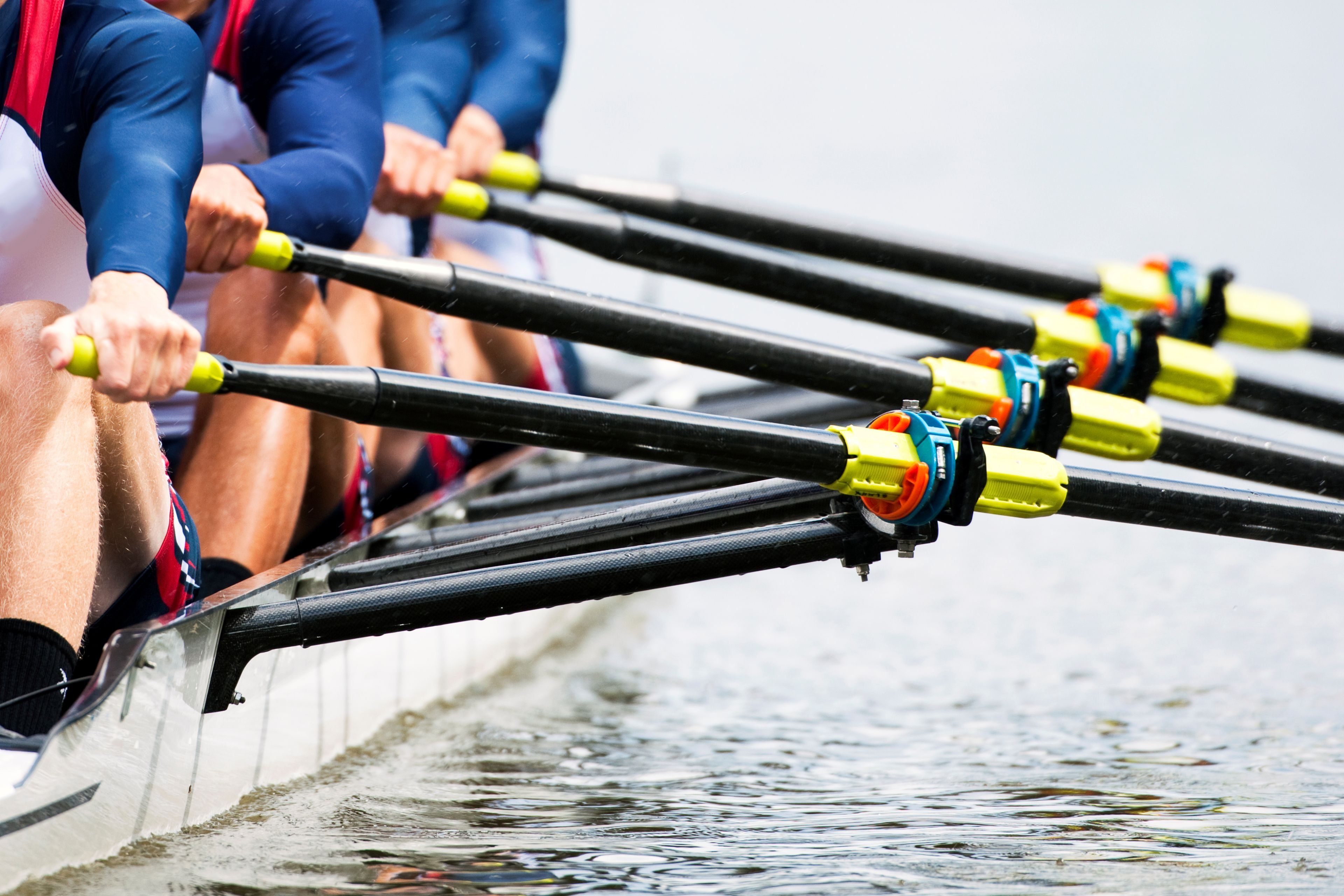 A rowing team in a boat with oars.