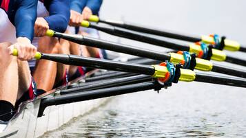 A rowing team in a boat with oars.