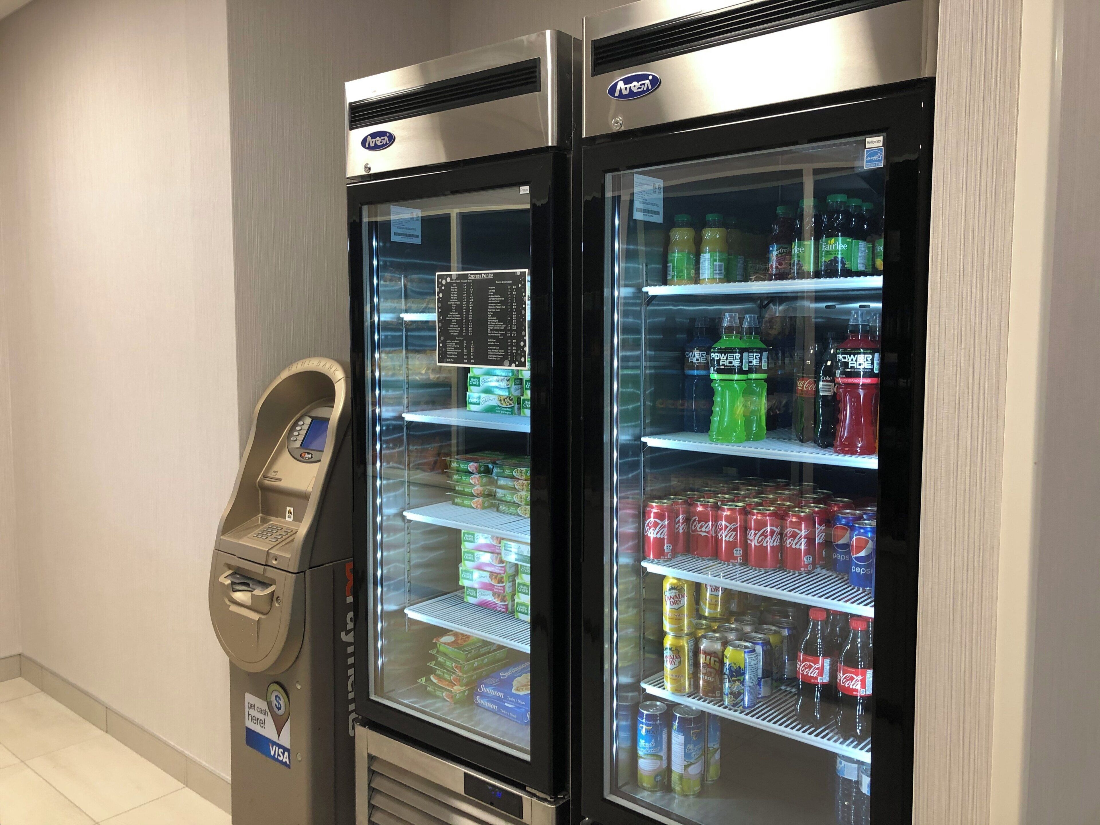 Two beverage vending machines with a payment terminal beside them.