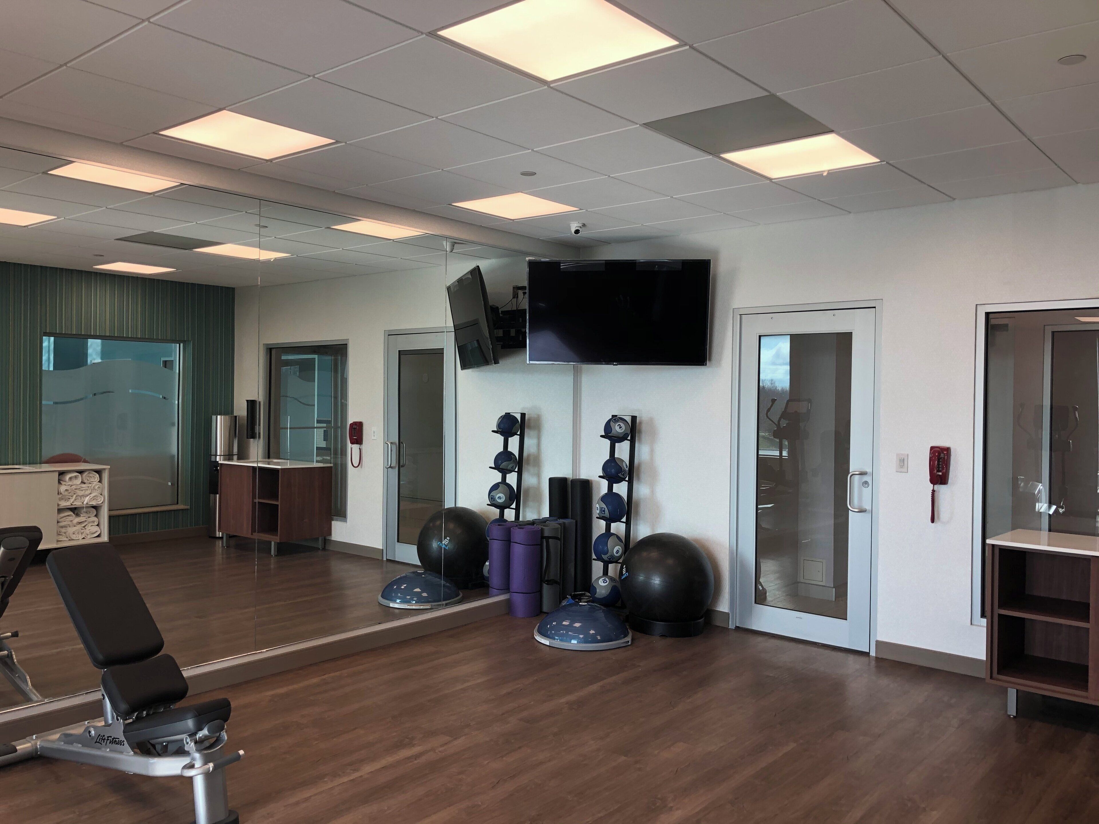 A gym with exercise equipment, a television, and a mirror.
