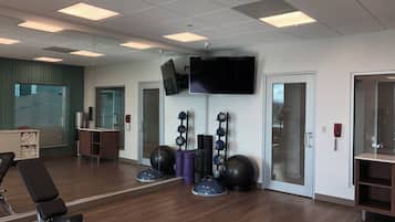 A gym with exercise equipment, a television, and a mirror.