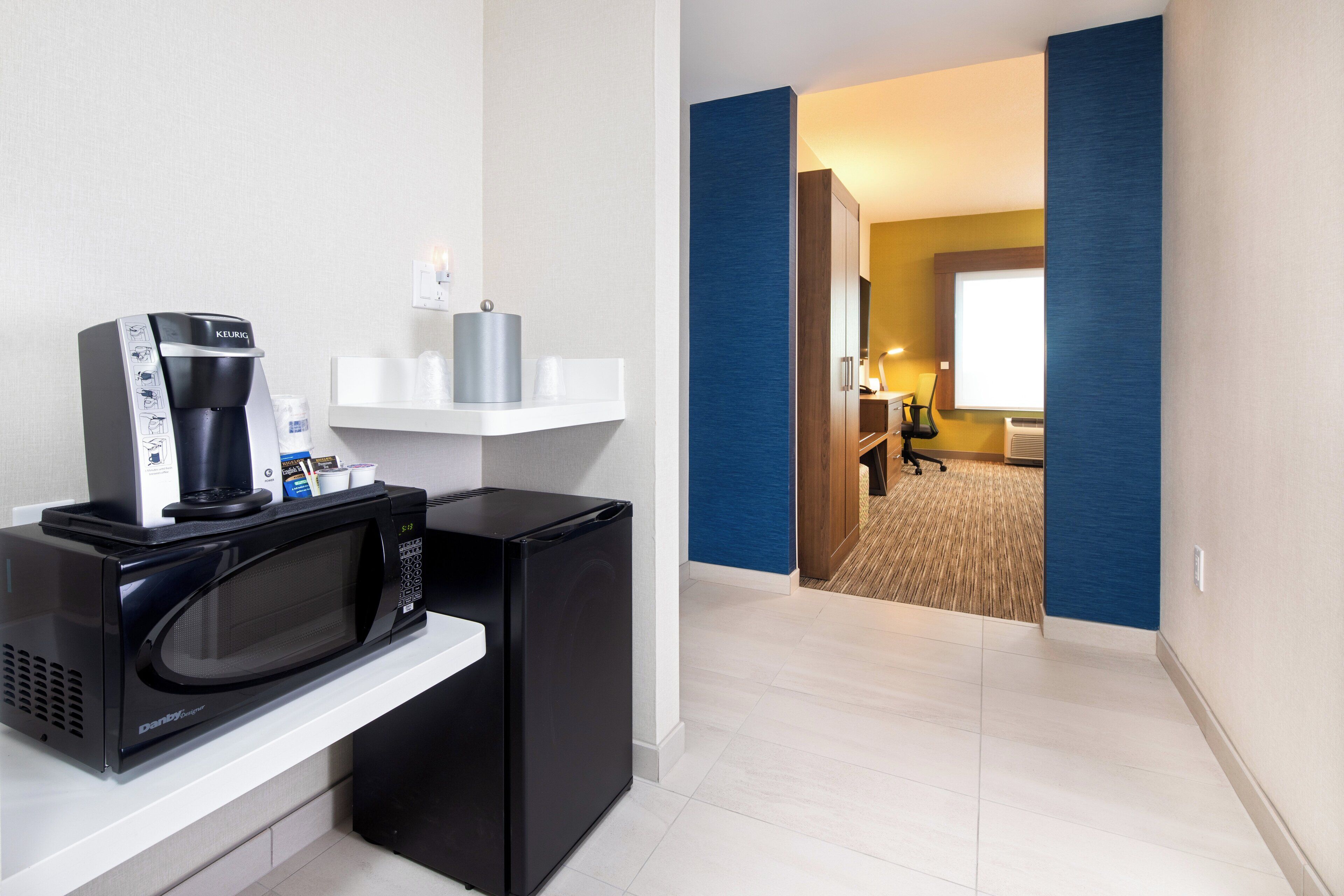 Une chambre d’hôtel dotée d’un coin cuisine comprenant un four à micro-ondes, une machine à café et un petit réfrigérateur.