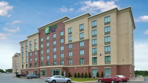 A Holiday Inn Express & Suites hotel with a brick facade, multiple windows, and a parking lot with several cars. - Holiday Inn Express & Suites Halifax Airport by IHG (Goffs)
