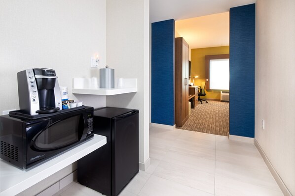 A kitchenette with a microwave, coffee maker, and a small refrigerator.