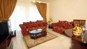 A living room with two sofas, a coffee table, a TV, and a fruit basket. - Royal Plaza Hotel Apartments (Dubai)