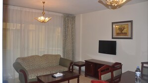 A living room with a sofa, a coffee table, a TV, and a cabinet. - Royal Plaza Hotel Apartments (Dubai)