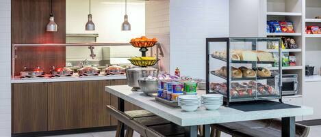 Une cuisine moderne dotée d’un îlot central, de tabourets de bar et d’une variété de produits alimentaires exposés.