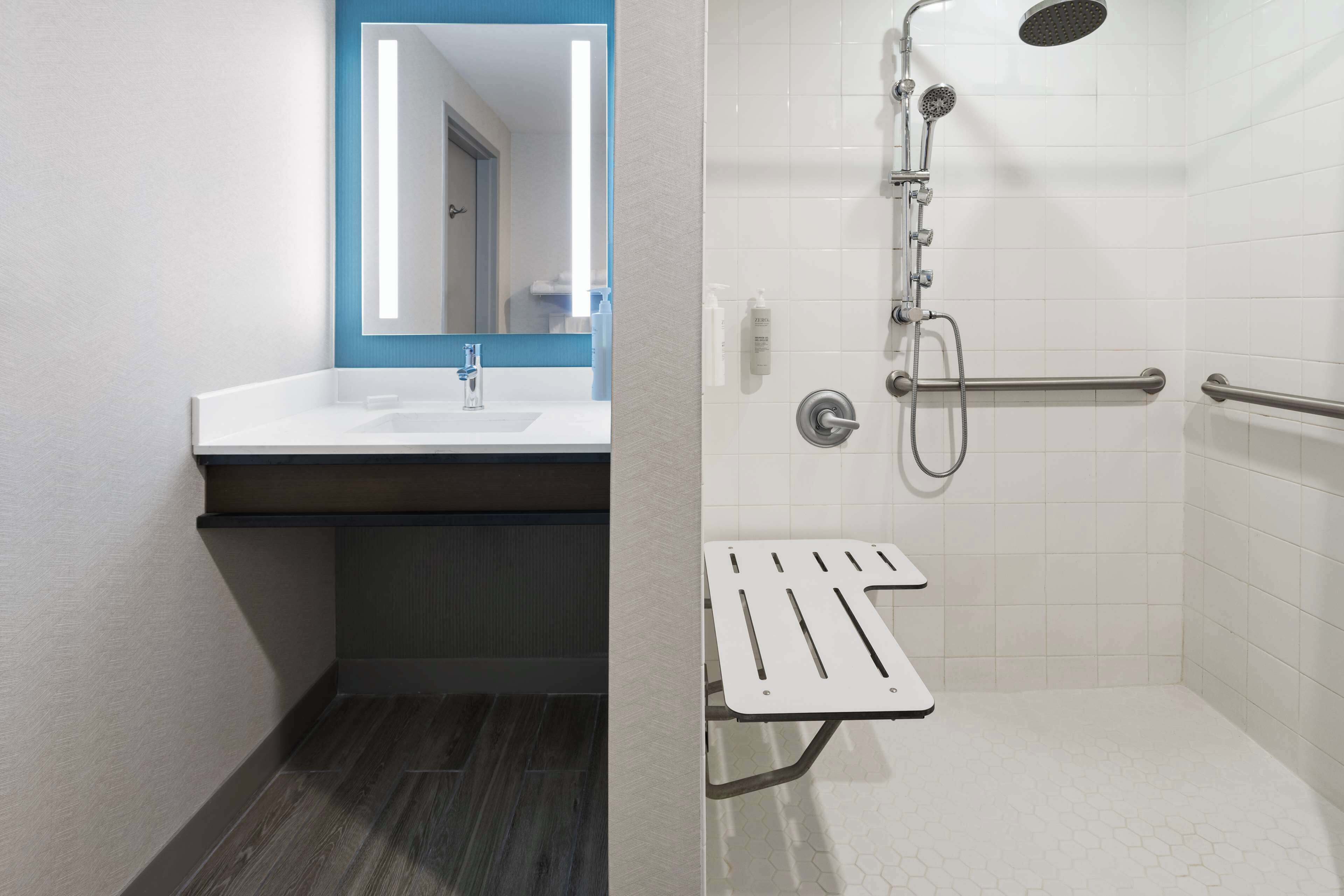 Un baño moderno con lavamanos, espejo y ducha blancos.