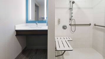 Un baño moderno con lavamanos, espejo y ducha blancos.