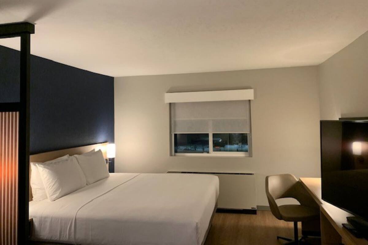 Une chambre d’hôtel moderne équipée d’un lit, d’un bureau et d’une télévision.
