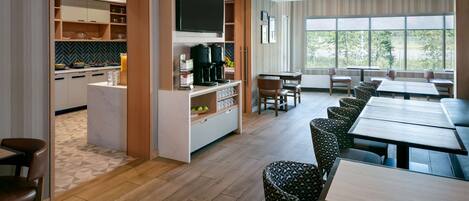 A modern hotel room with a kitchen, dining area, and large windows.