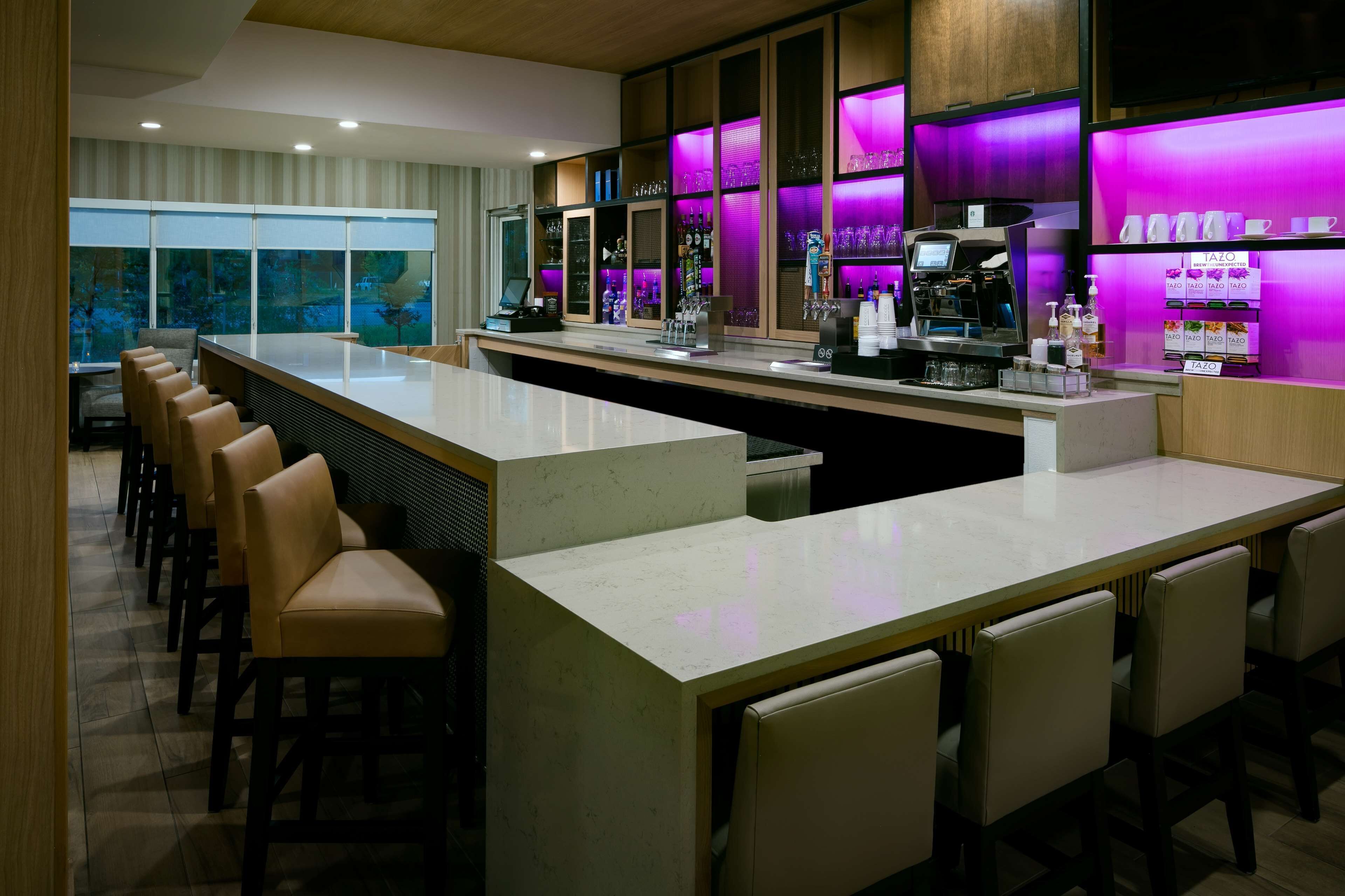 A bar area with a long counter, multiple seating options, and a variety of bar tools and bottles.