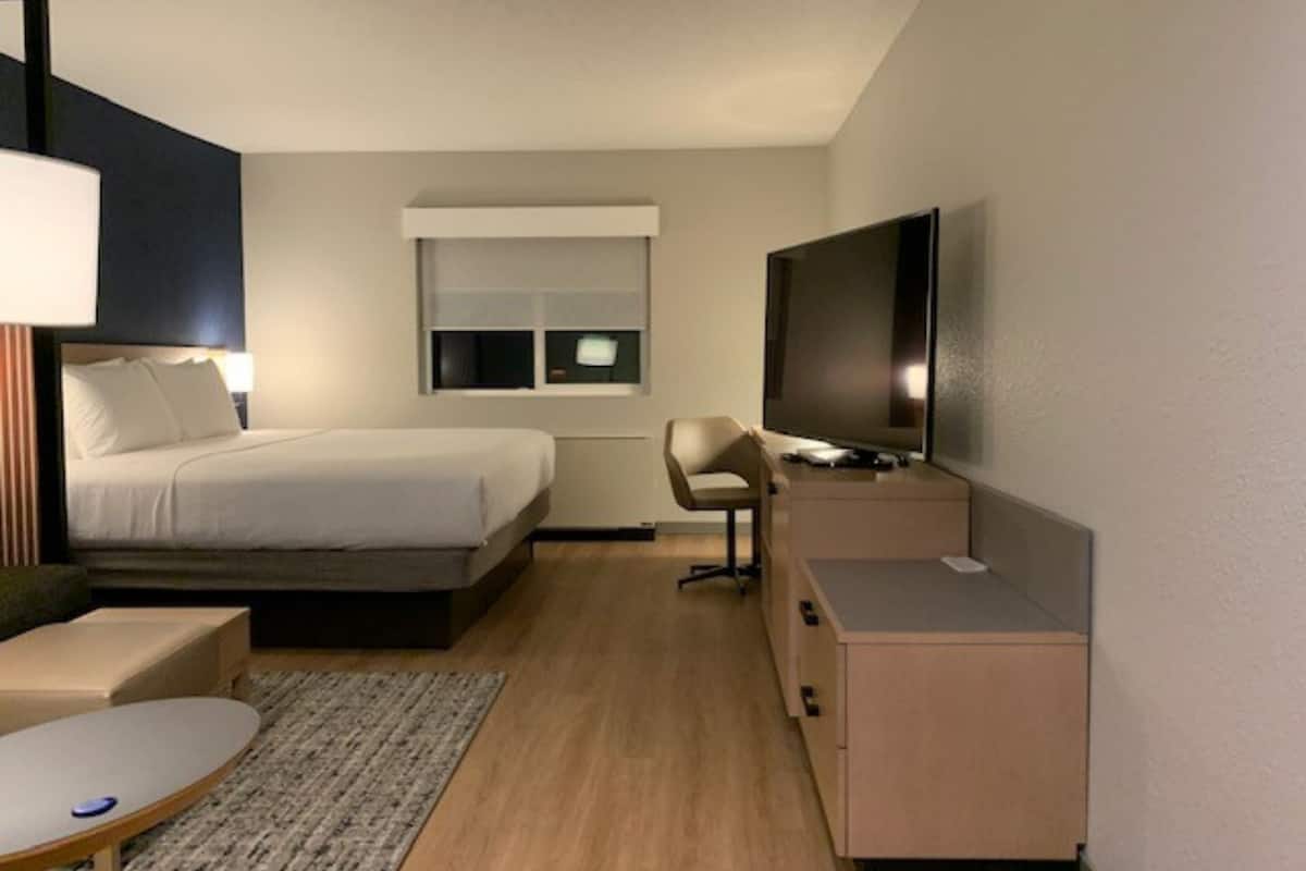 Une chambre d’hôtel moderne équipée d’un lit, d’un bureau, d’une télévision et d’une fenêtre.