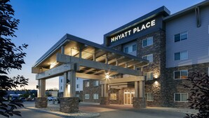 Una entrada moderna de hotel con un corredor cubierto, fachada de piedra y un letrero claro que dice "HYATT PLACE".
