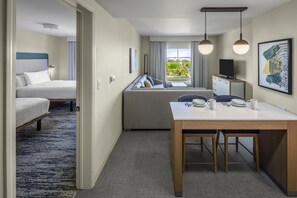 A hotel room with a bed, a desk with a chair, a dining table, and a view of the outdoors. - Homewood Suites by Hilton Denver Tech Center (Englewood)