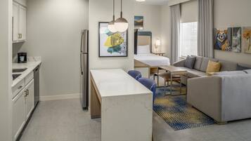 A modern hotel room with a kitchenette, a dining area, a sofa, and a bed.