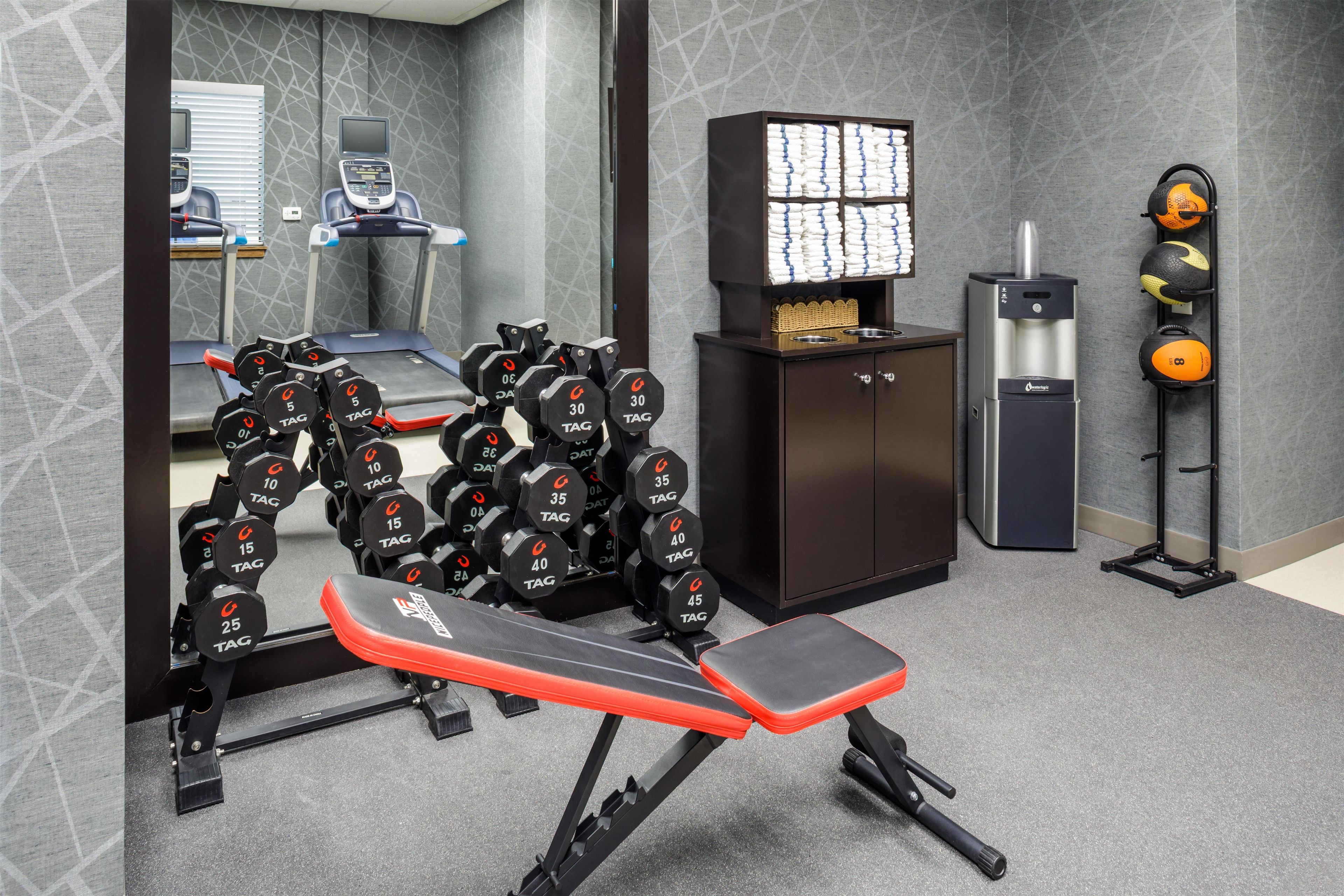 A gym with weightlifting equipment, treadmills, and a water dispenser.
