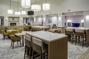A hotel lobby with multiple seating areas, a fireplace, and a television mounted on the wall. - Homewood Suites by Hilton Denver Tech Center (Englewood)