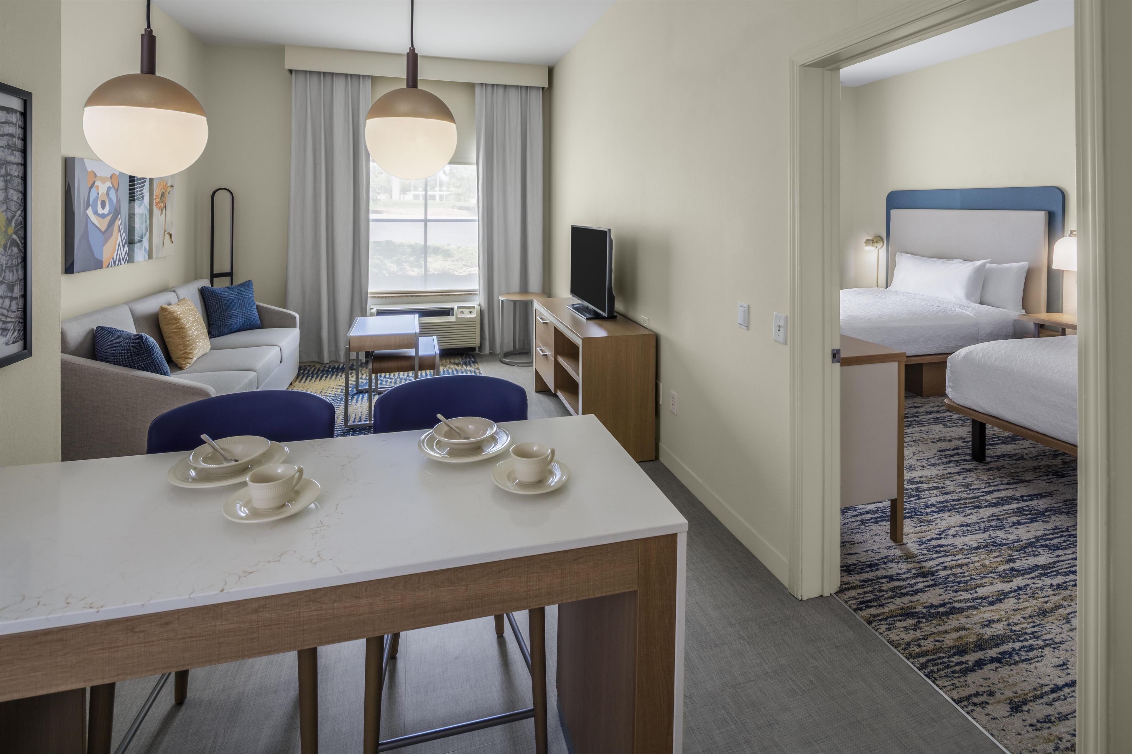 Une chambre d’hôtel équipée d’une table à manger, d’un canapé, d’une télévision et d’un lit.