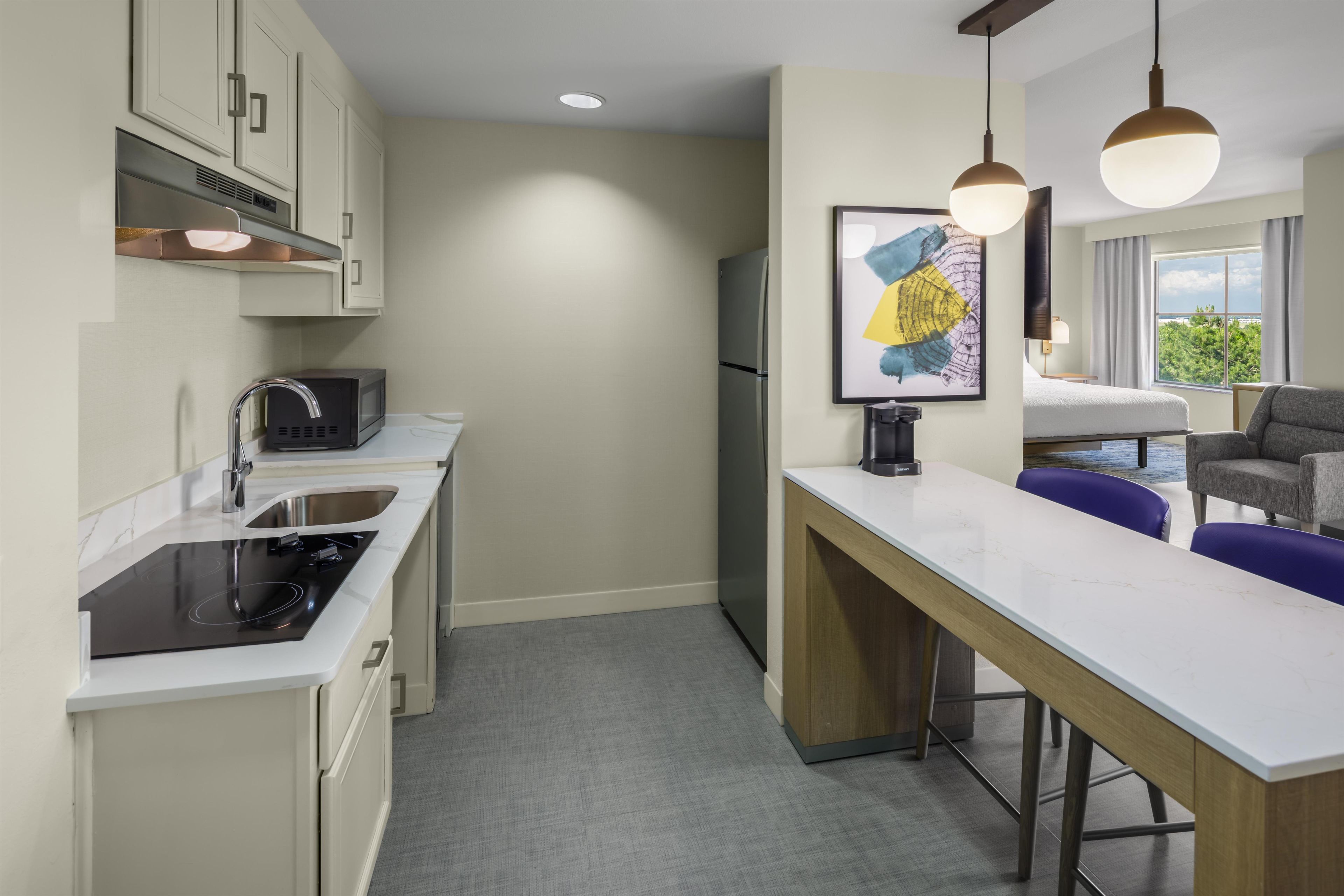 A compact kitchen with a microwave, sink, and stove, a small dining area with a table and chairs, and a refrigerator.