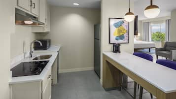 A compact kitchen with a microwave, sink, and stove, a small dining area with a table and chairs, and a refrigerator.