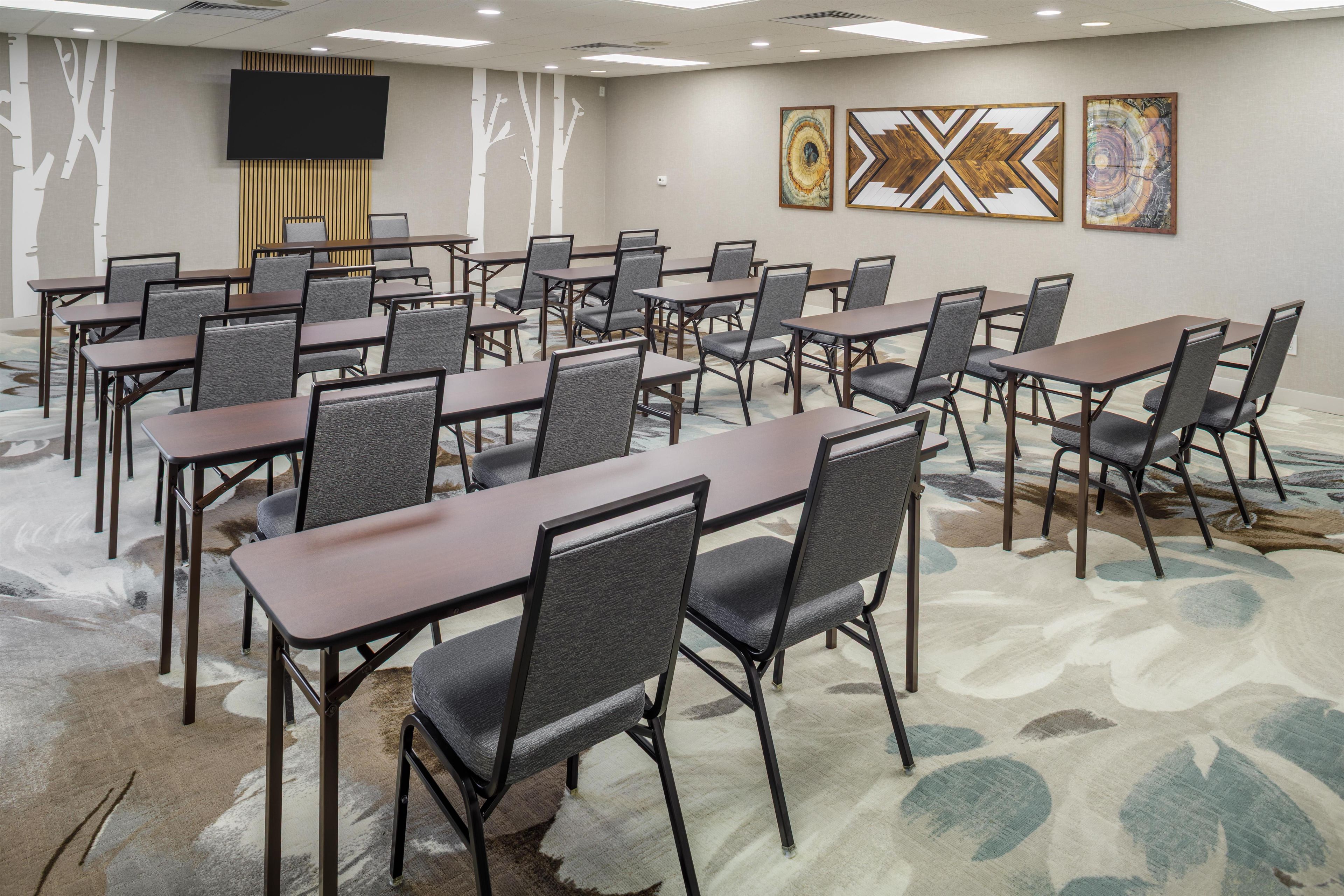 Une salle de conférence équipée de plusieurs tables et chaises, d’un téléviseur à écran plat et d’œuvres d’art abstraites accrochées aux murs.