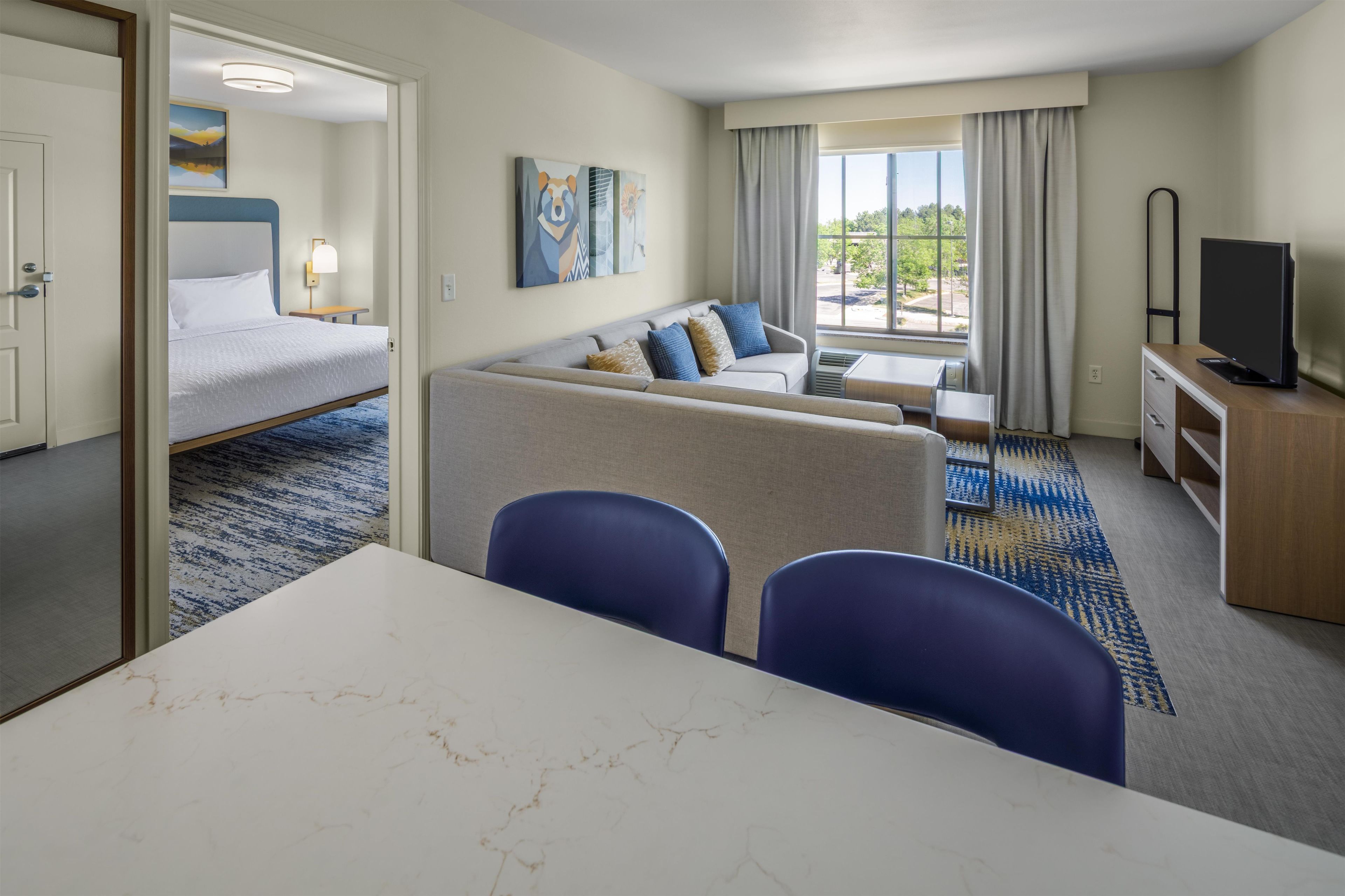 Una habitación de hotel con una cama, un sofá, una mesa de comedor y un televisor.