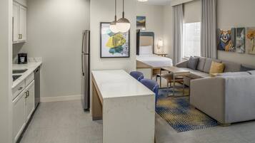 Une chambre d’hôtel moderne équipée d’une kitchenette, d’un coin repas, d’un canapé et d’un lit.
