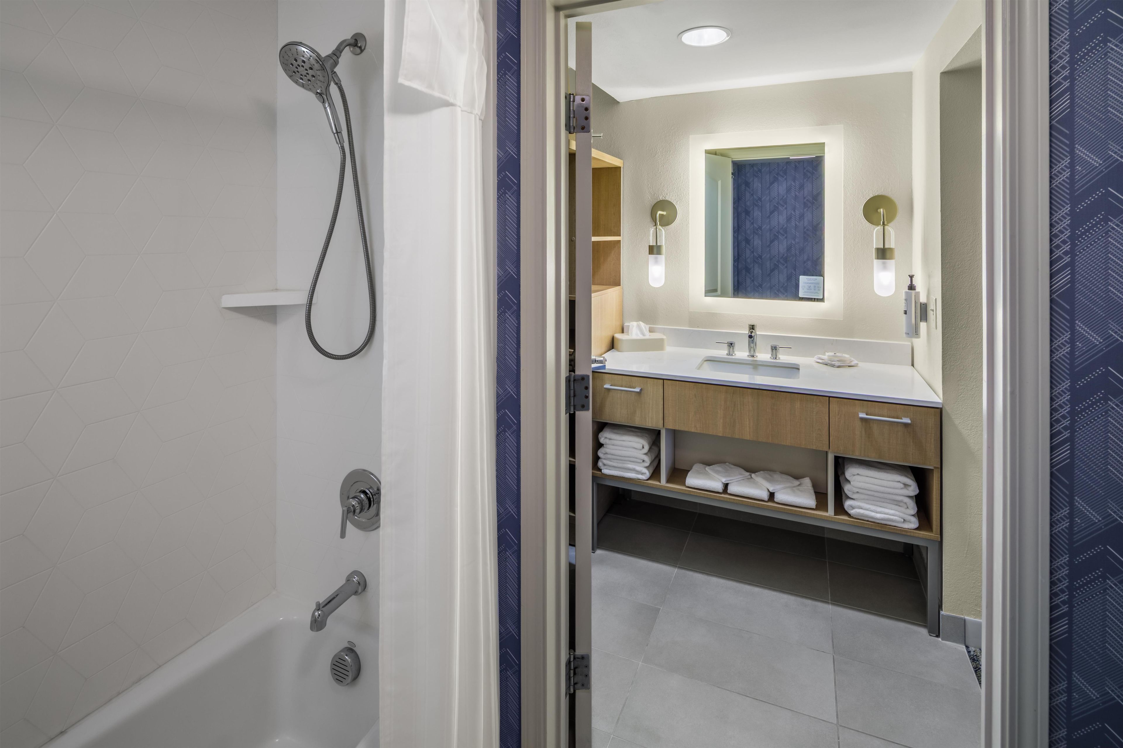 Une salle de bain moderne équipée d’une douche, d’un lavabo et d’un espace pour ranger les serviettes.