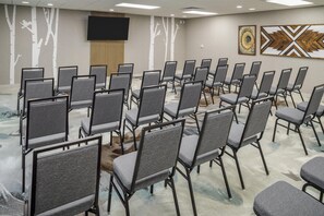 A conference room with rows of grey chairs, a large flat-screen TV on the wall, and two abstract paintings. - Homewood Suites by Hilton Denver Tech Center (Englewood)