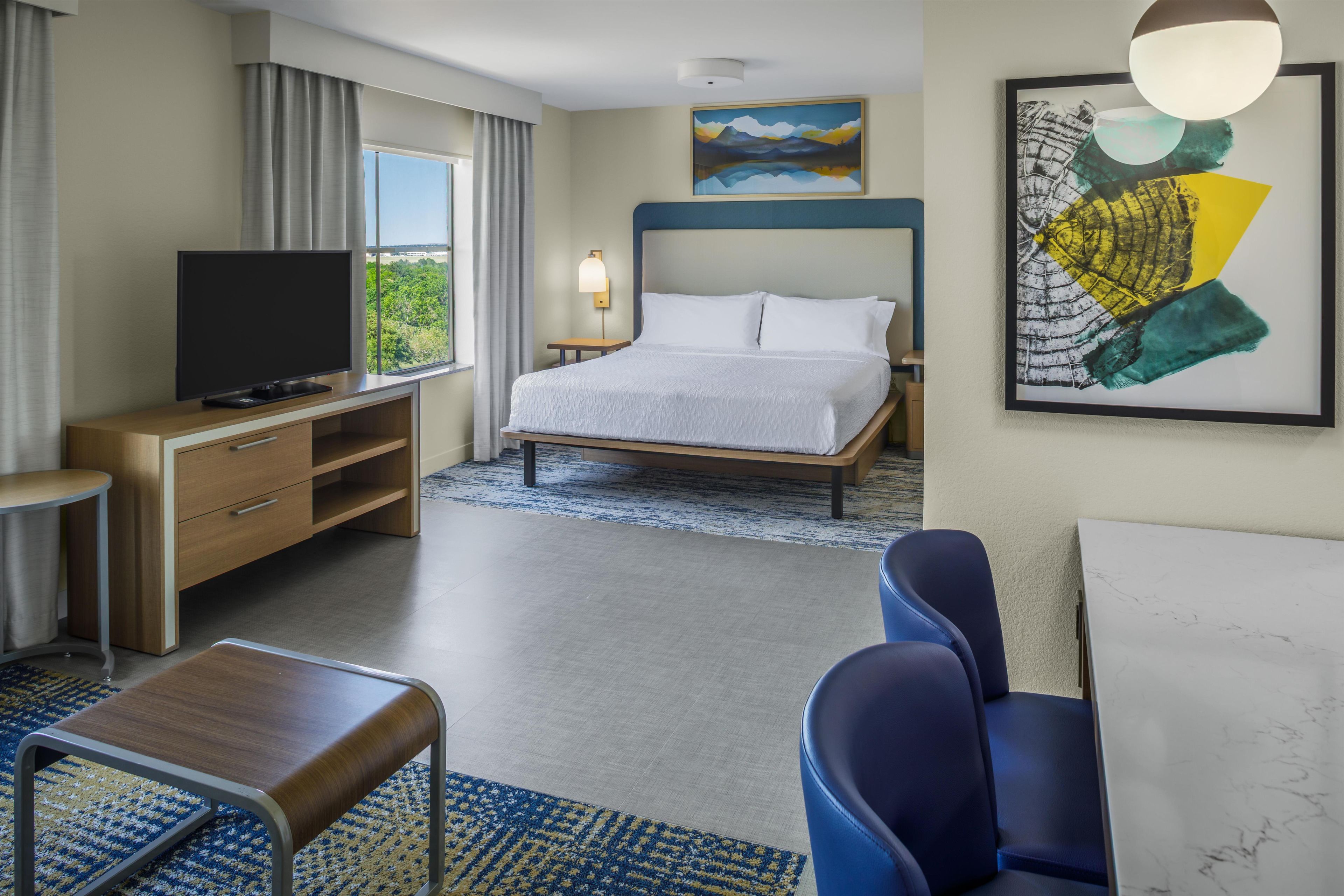 Habitación de hotel con cama, televisión, escritorio y zona de estar.