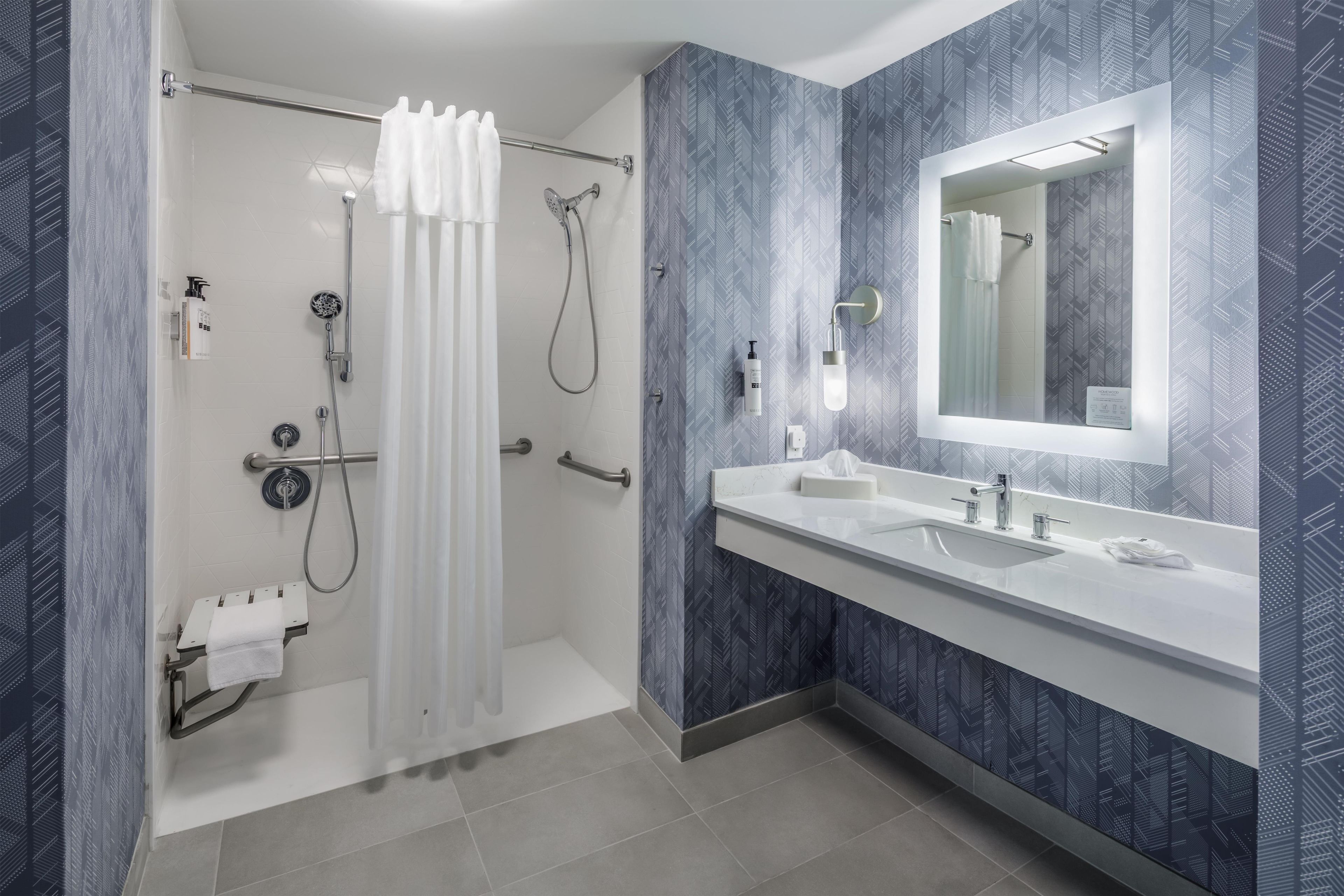 A modern bathroom with a shower, a large mirror, and a vanity with two sinks.