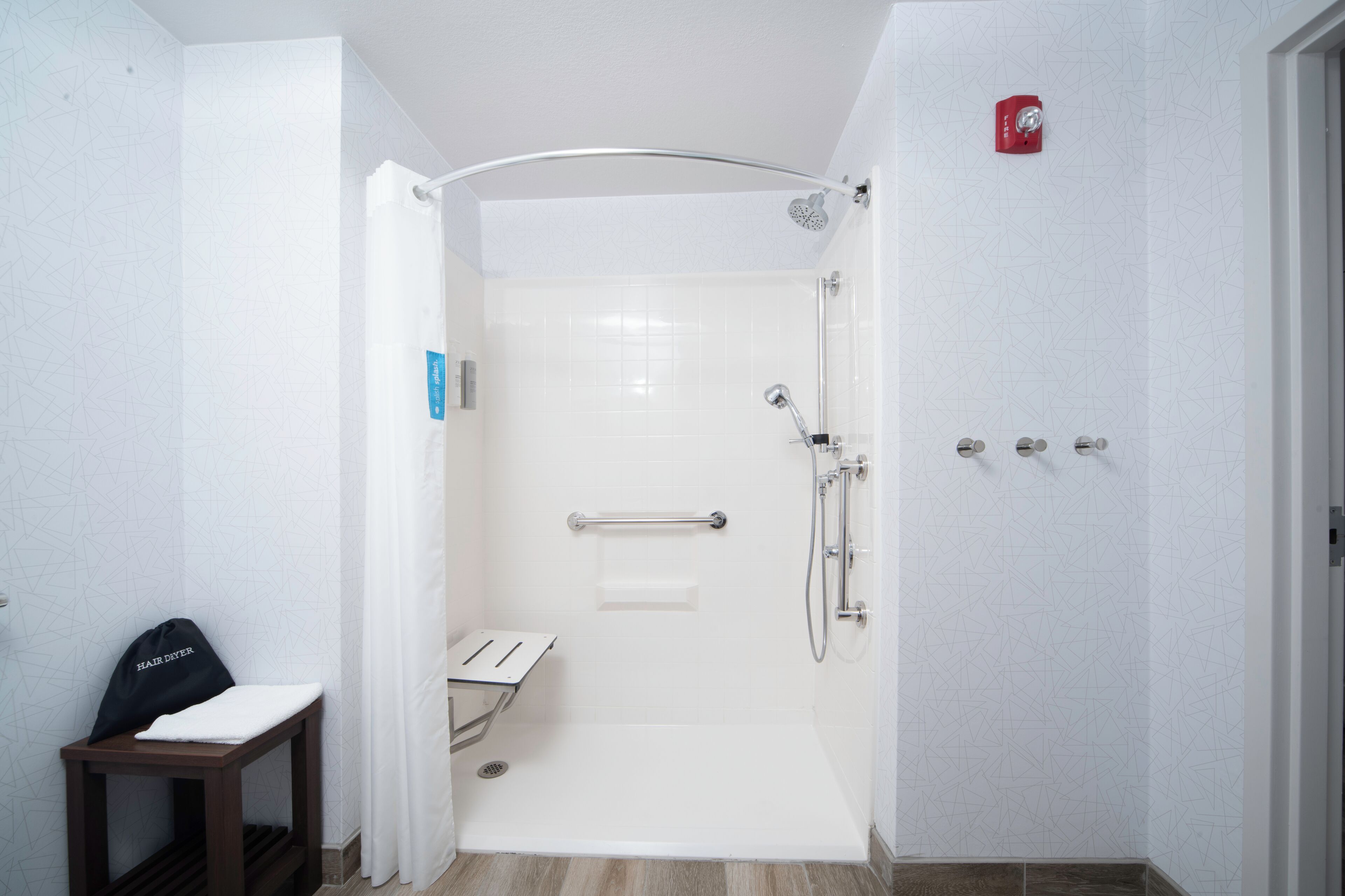 Eine begehbare Dusche mit Glastür, Handtuchhalter und Sitzbank.