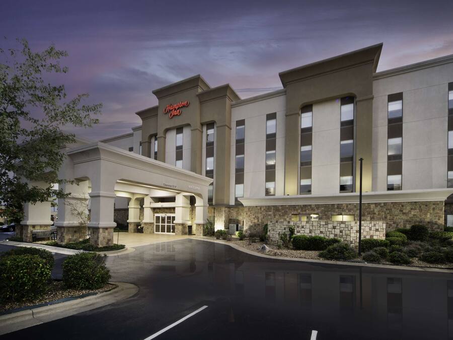 A modern hotel with a prominent entrance, a well-lit facade, and a landscaped driveway.