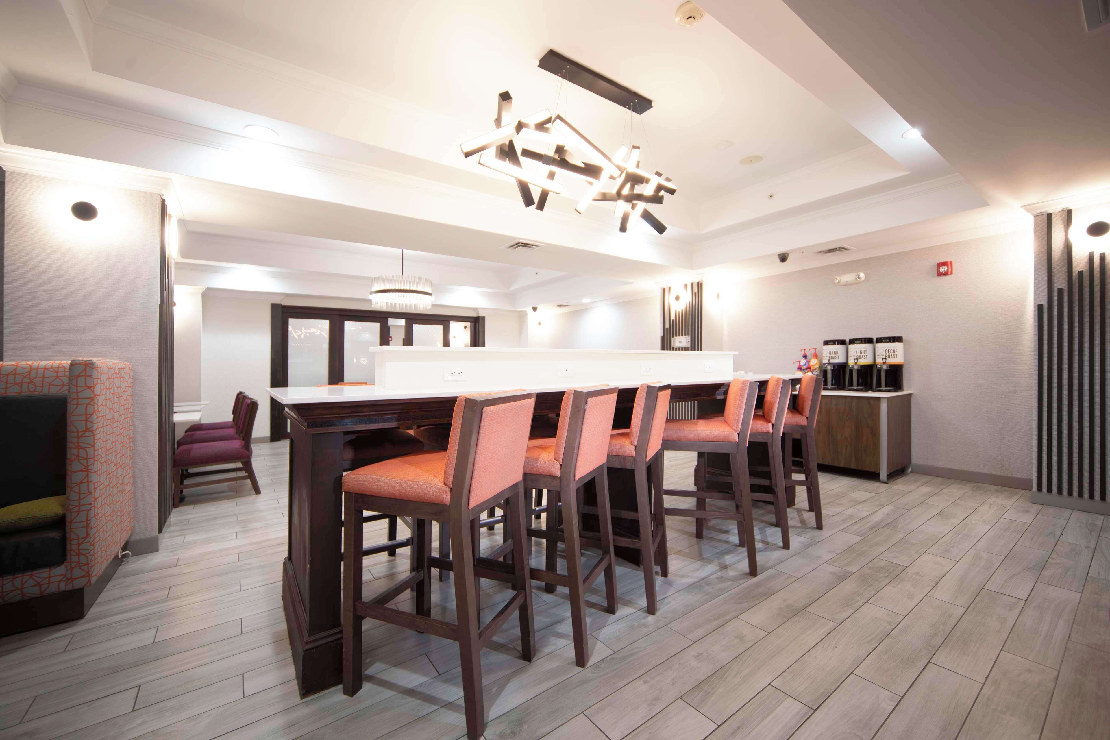 A modern kitchen with a central island, bar stools, and a seating area with a sofa and chairs.