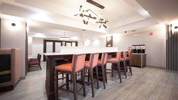 A modern kitchen with a central island, bar stools, and a seating area with a sofa and chairs.