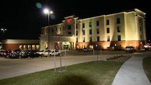 A multi-story hotel with a prominent sign, parking lot, and well-lit exterior. - Hampton Inn Topeka (Topeka)