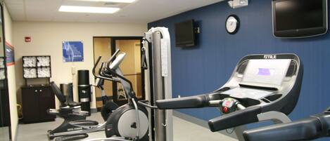 Une salle de sport équipée de divers appareils d’exercice, notamment des tapis de course et des vélos d’appartement.