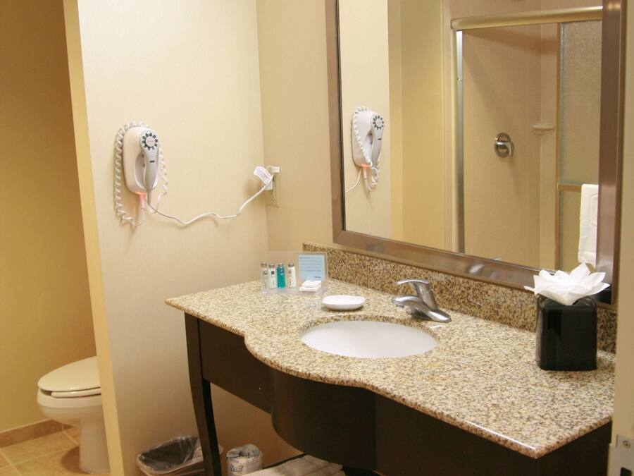 A bathroom with a sink, mirror, hairdryer, and towel rack.