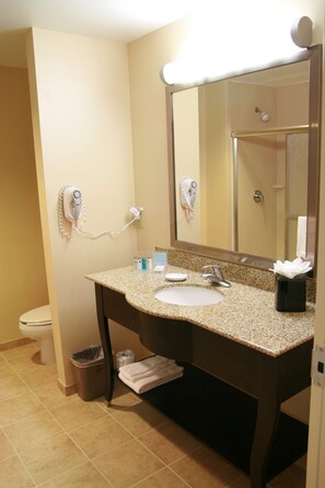 A bathroom with a sink, mirror, hairdryer, and towel rack.