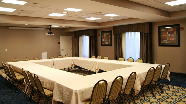 Una sala de conferencias con una mesa larga, sillas y un proyector.