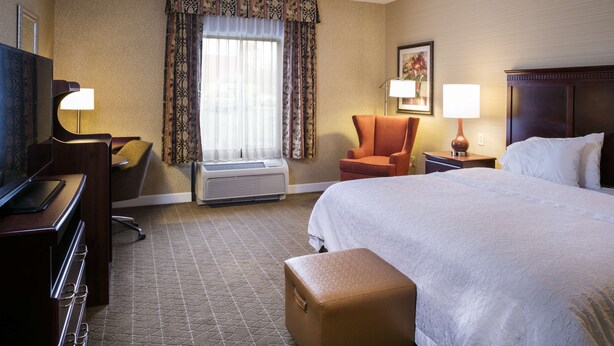 A hotel room with a bed, a desk with a computer, an air conditioner, a chair, and a television. - Hampton Inn & Suites Toledo-Perrysburg (Perrysburg)