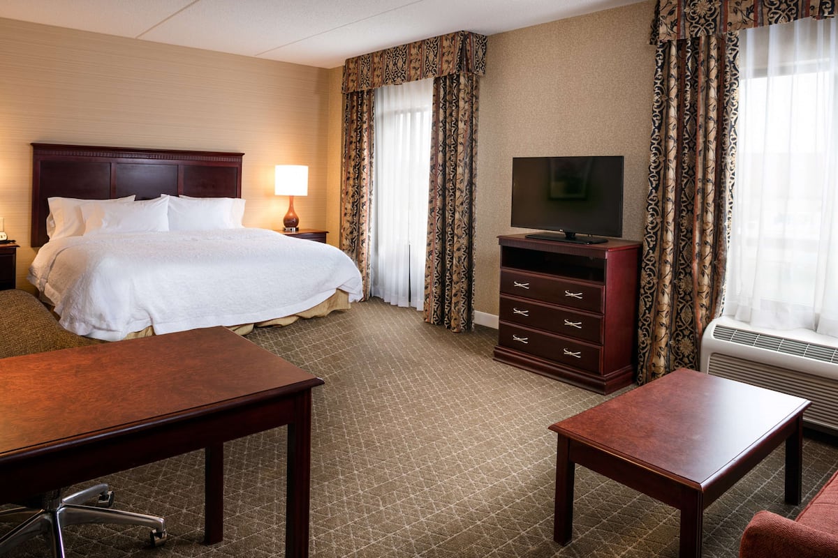 A hotel room with a large bed, a TV, a desk, and a dresser.