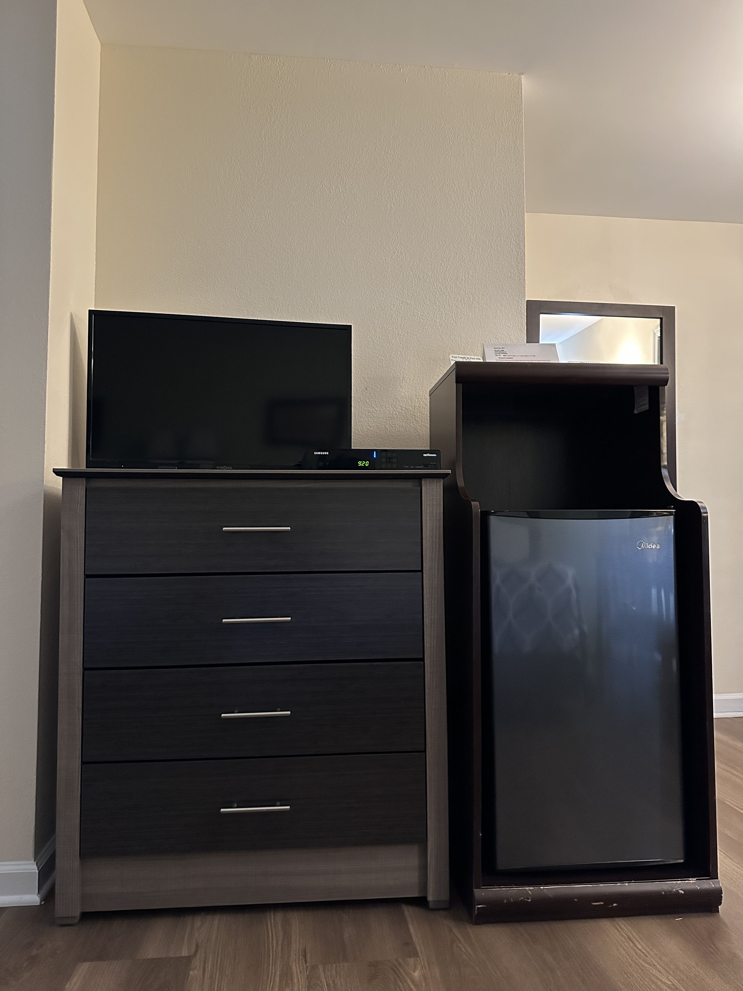 A dark wooden dresser with drawers and a flat-screen TV on top.