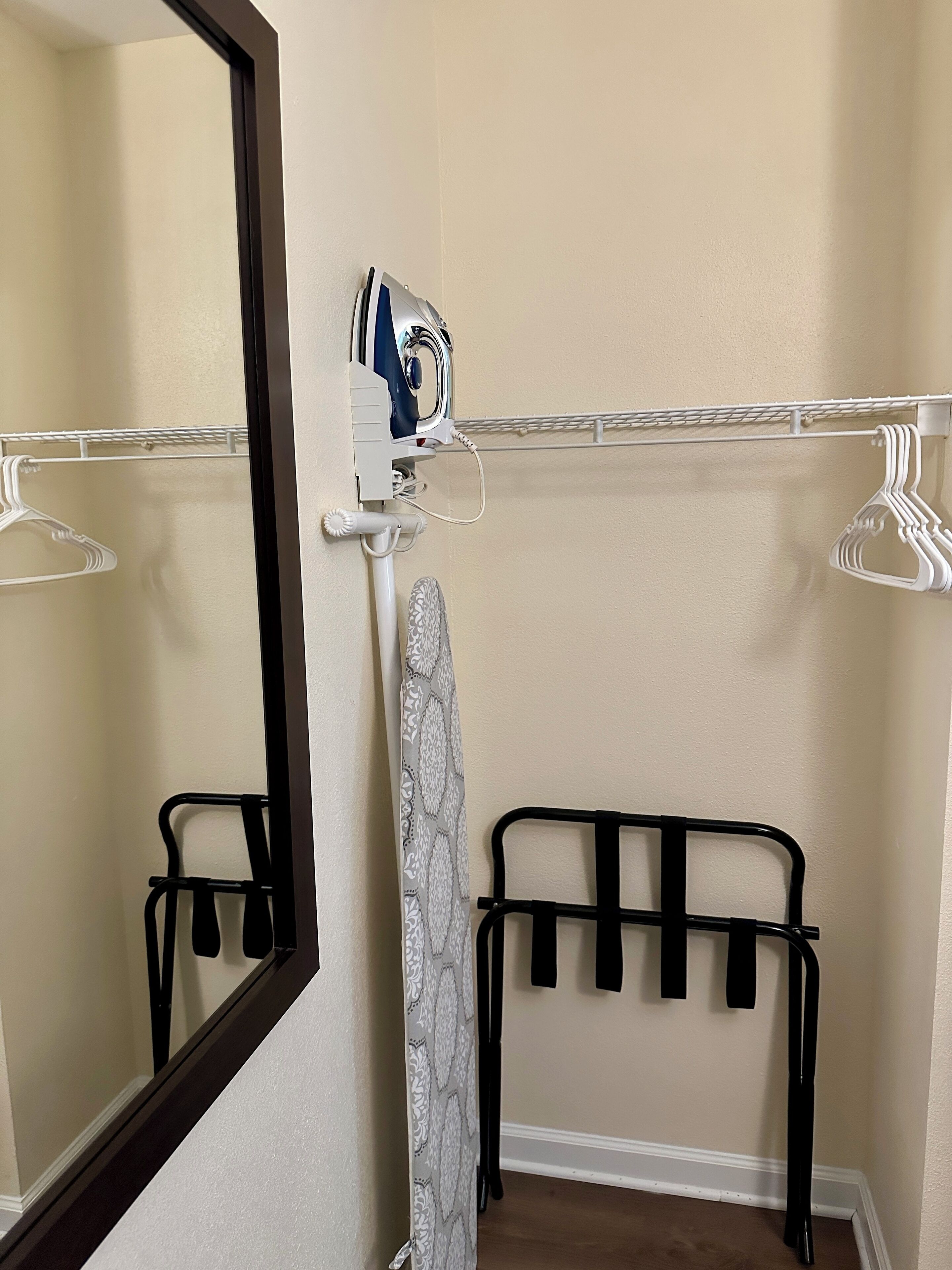 A bathroom with a mirror, a towel rack, a shower curtain, and a black metal rack for hanging items.