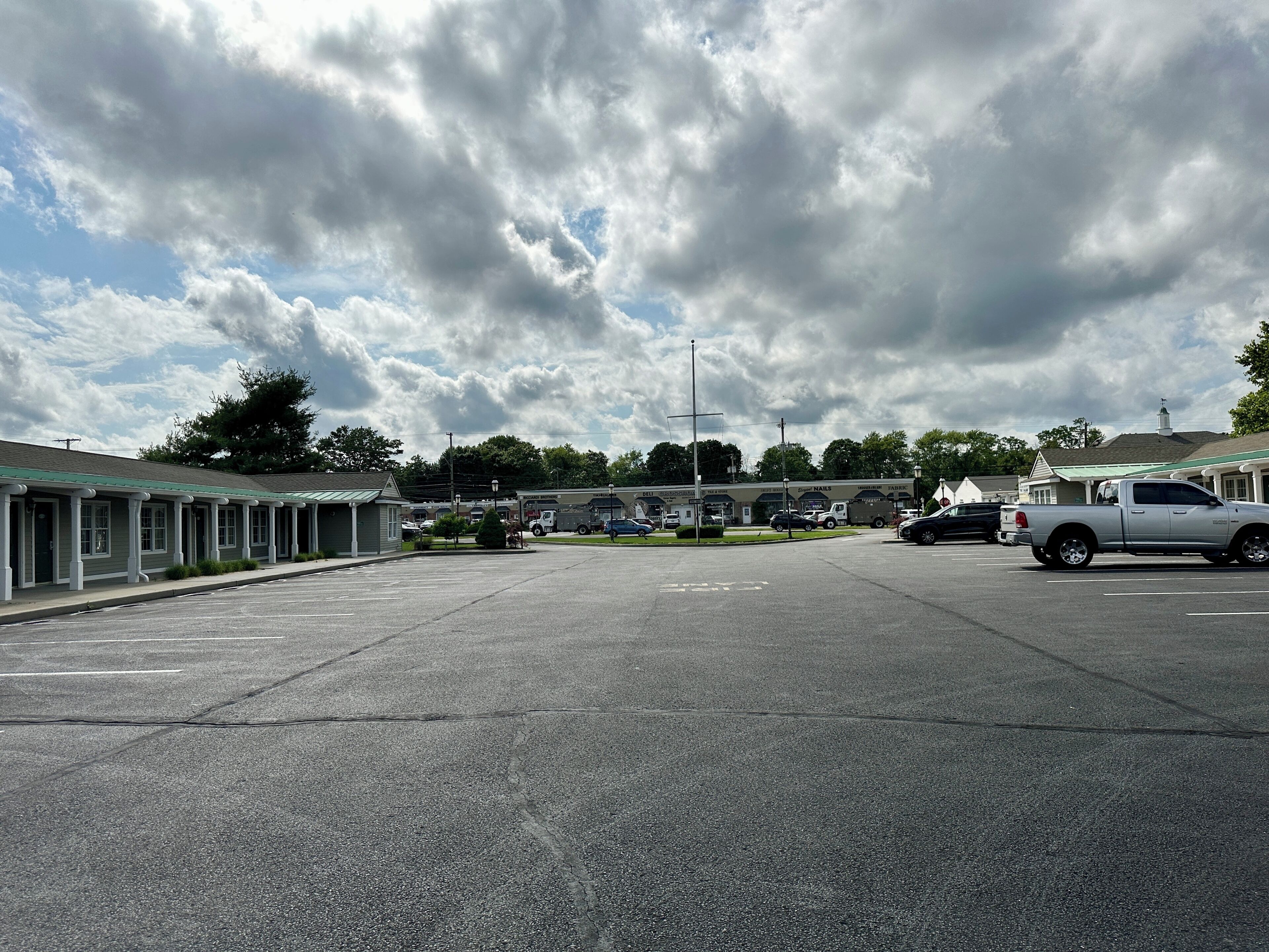 A parking lot with a row of small, single-story buildings with green roofs, likely a motel or inn.